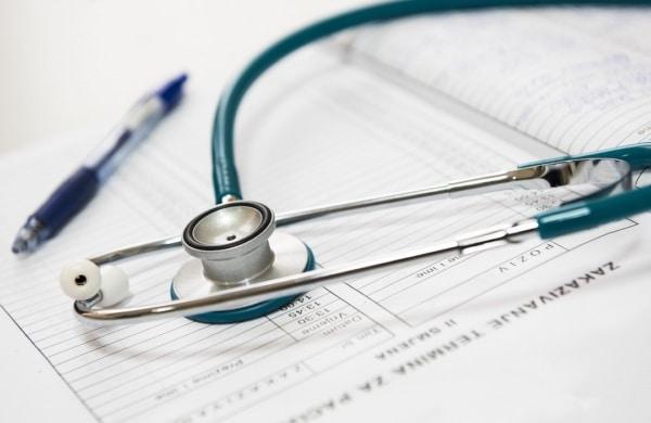 A doctor's stethoscope with medical forms that resemble travel insurance forms
